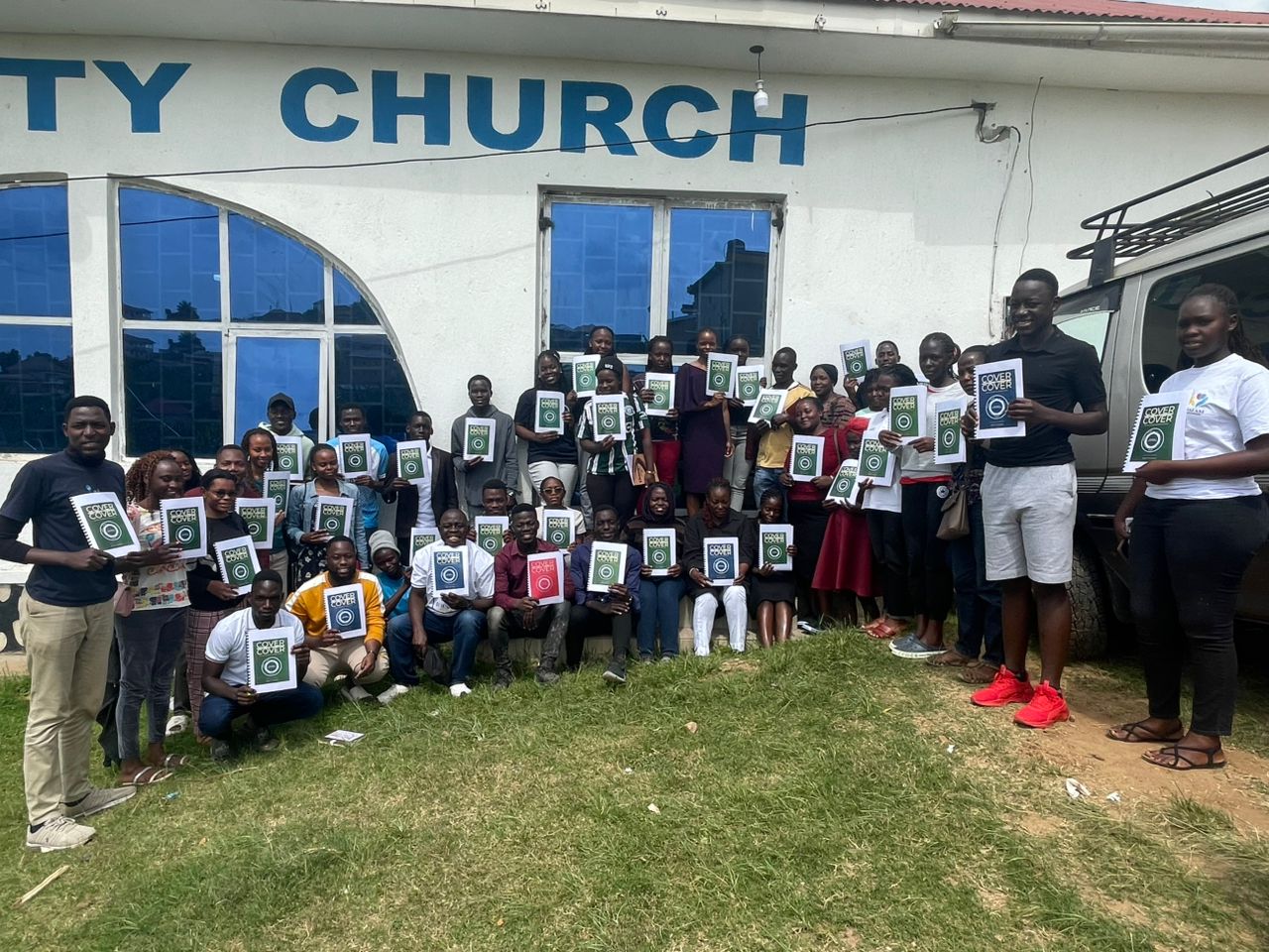 Students in Ishaka, Uganda, holding their Cover to Cover workbooks